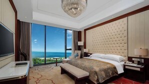 A hotel room with a large bed, a bench, a TV, a desk, and a view of the ocean. - Jinling Haizhou Bayview Conference Center (Lianyungang)