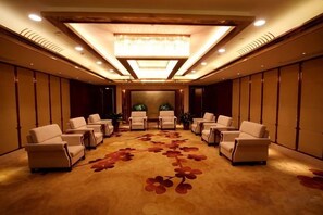 A conference room with a carpeted floor, multiple chairs arranged in rows, a chandelier, and a plant in the center. - Jinling Haizhou Bayview Conference Center (Lianyungang)