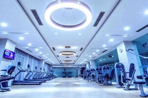 Un gimnasio con cintas de correr, elípticas y una pantalla de televisión en la pared.