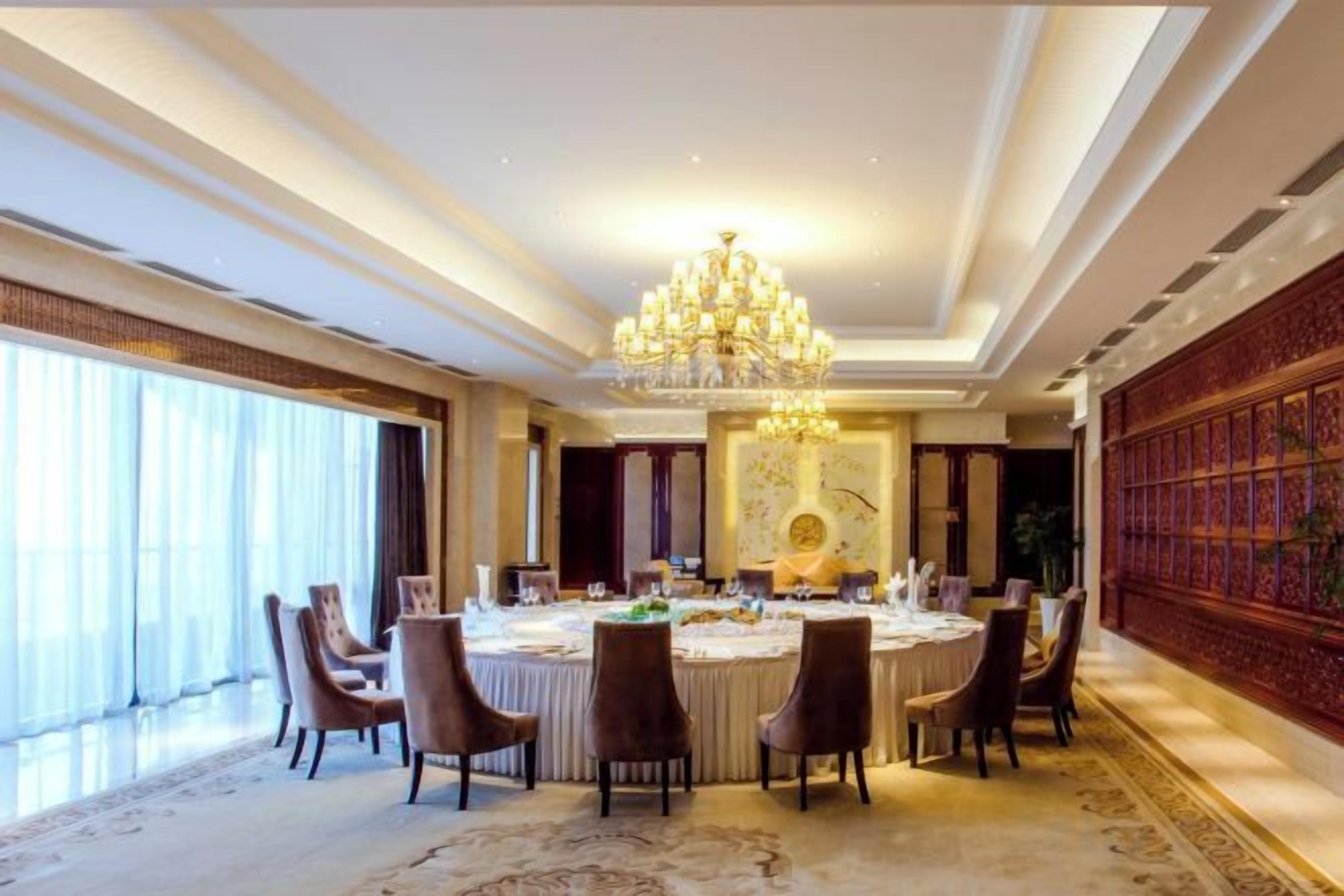 A formal dining room with a chandelier, round table, and chairs.