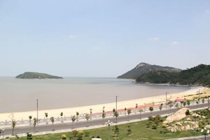Una carretera costera con una playa y colinas al fondo.