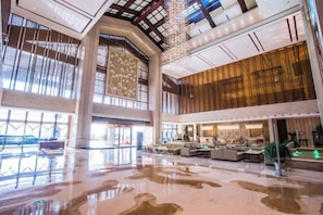 A spacious lobby with high ceilings, large windows, and a central seating area.