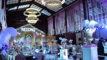 An indoor venue with a stage labeled 'WEDDING' and multiple tables set up for guests.