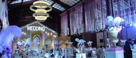 Un espacio interior con un escenario que dice 'BODA' y varias mesas dispuestas para los invitados.