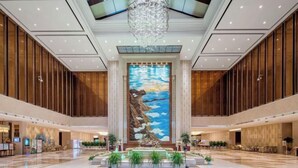 A spacious lobby with a large mural, a fountain, and a chandelier. - Jinling Haizhou Bayview Conference Center (Lianyungang)