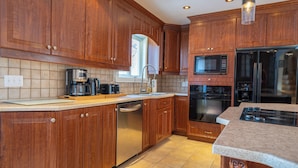 A kitchen with wooden cabinets, a dishwasher, a microwave, and a refrigerator. - Spacious - 3 bedrooms house in Granby, Quebec (Granby)