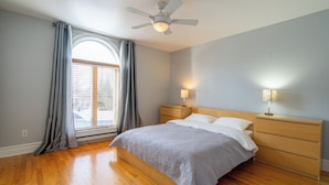 A bedroom with a bed, wooden nightstands, a ceiling fan, a window with curtains, and a lamp. - Spacious - 3 bedrooms house in Granby, Quebec (Granby)