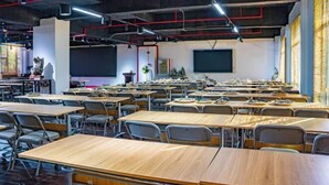 A classroom with desks and chairs arranged in rows, a projector screen, and a whiteboard. - Stone Hotel (Yingde)
