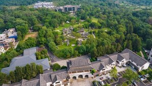 An aerial view of a residential area with traditional architecture, surrounded by lush greenery and hills. - Stone Hotel (Yingde)