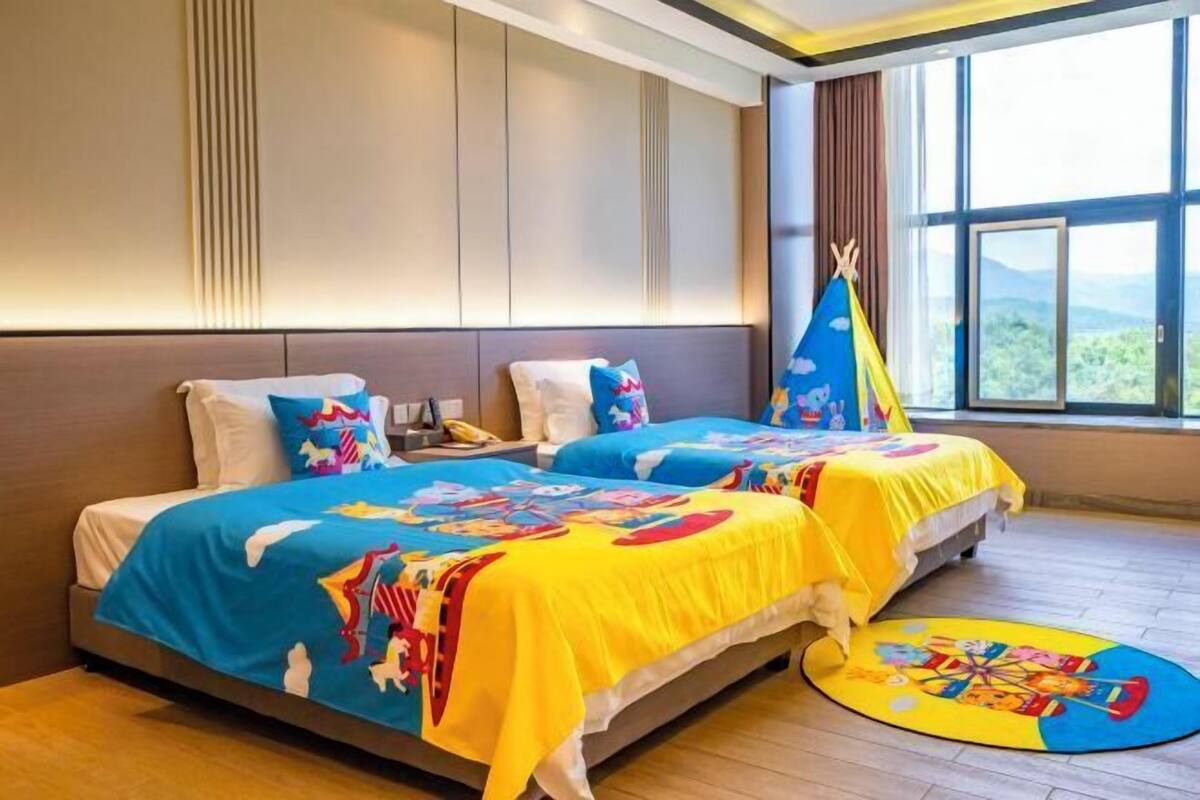 A hotel room with two beds, a large window, and a view of the outdoors.