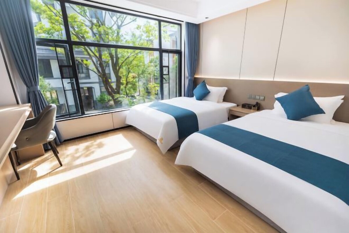 A hotel room with two beds, a desk, and a chair.