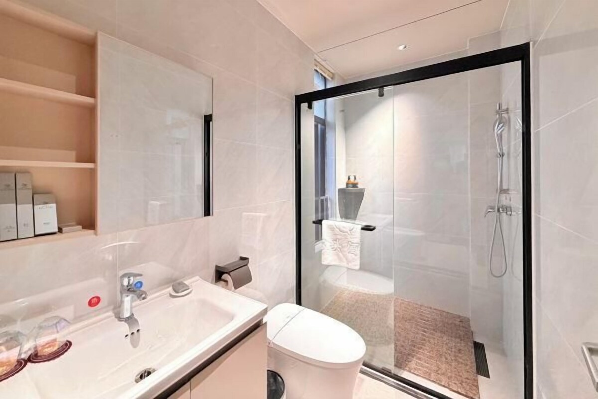 A modern bathroom with a glass-enclosed shower, a white sink, and a toilet.
