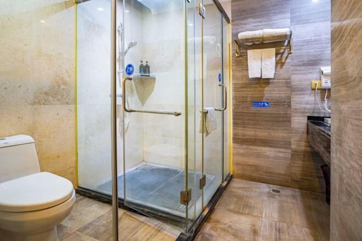 A bathroom with a glass-enclosed shower, a toilet, and a towel rack.