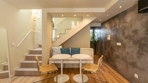 A modern interior with a staircase, a sofa with two round tables, and a textured wall.