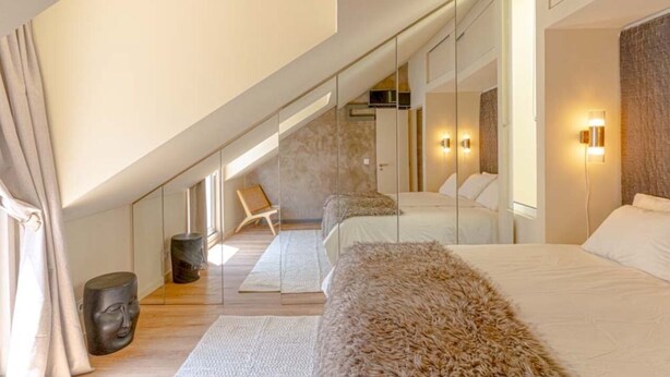 A modern bedroom with a large bed, a chair, and a mirror.