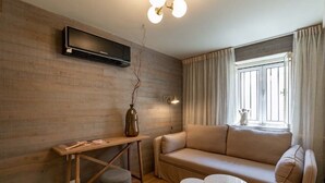 A modern living room with a sofa, a small table, a wooden desk, and a wall-mounted TV.