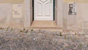 A building entrance with a white door, a number '28' above it, and a cobblestone pavement in front.