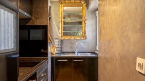 A compact kitchen with a built-in oven, a sink, and a mirror above it.