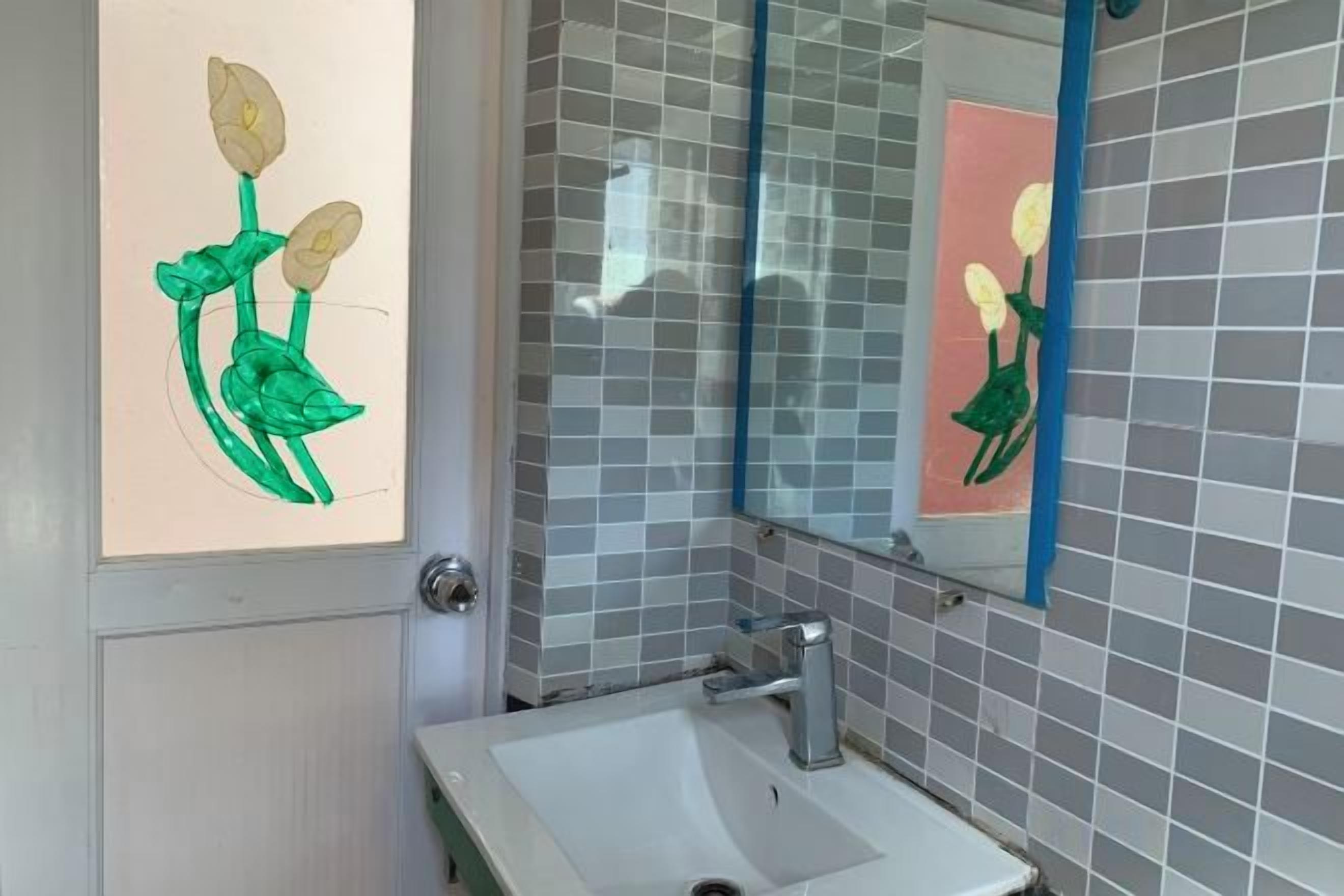 A bathroom with a sink, mirror, and decorative wall tiles.