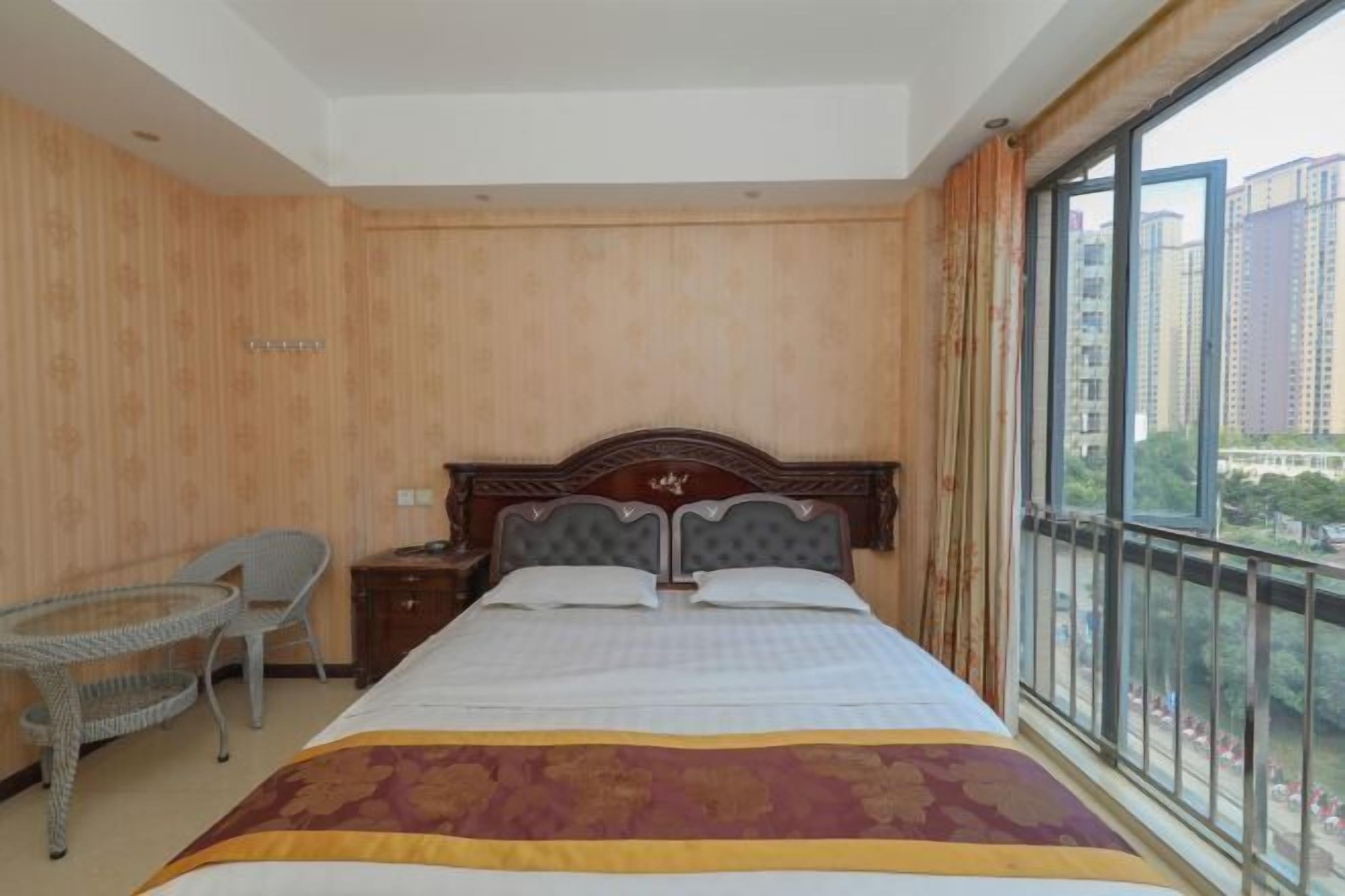 A hotel room with a large bed, a small table, and a chair.