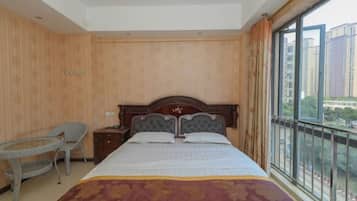 A hotel room with a large bed, a small table, and a chair.