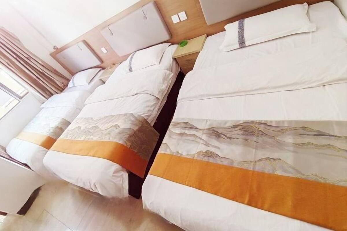 A hotel room with two beds, each with white bedding and a yellow accent.