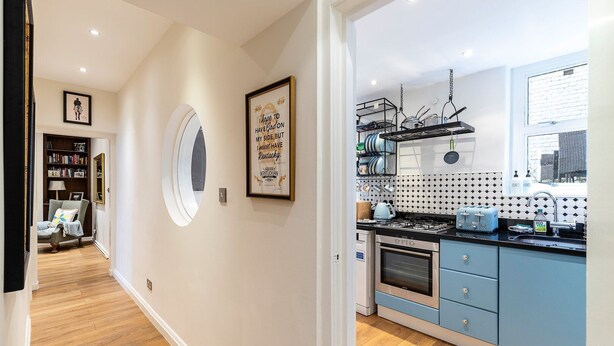A modern kitchen with blue cabinets, a built-in oven, and a window with a view of the city.