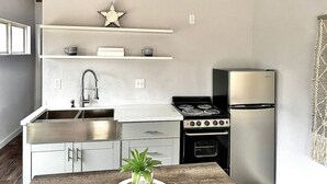 Una cocina compacta con pileta de acero inoxidable, estufa y refrigerador.