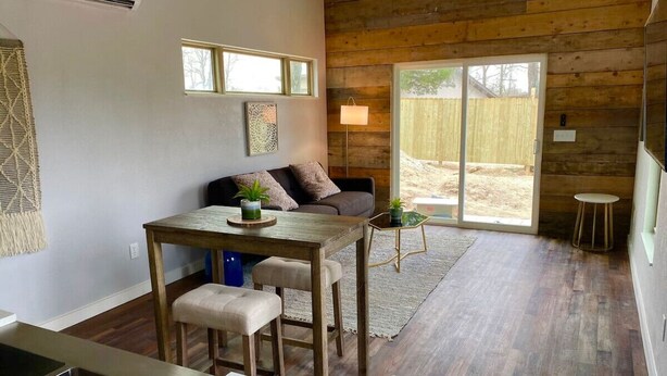 Una zona de estar acogedora con una mesa de madera, un sofá y una mesita auxiliar con una lámpara.