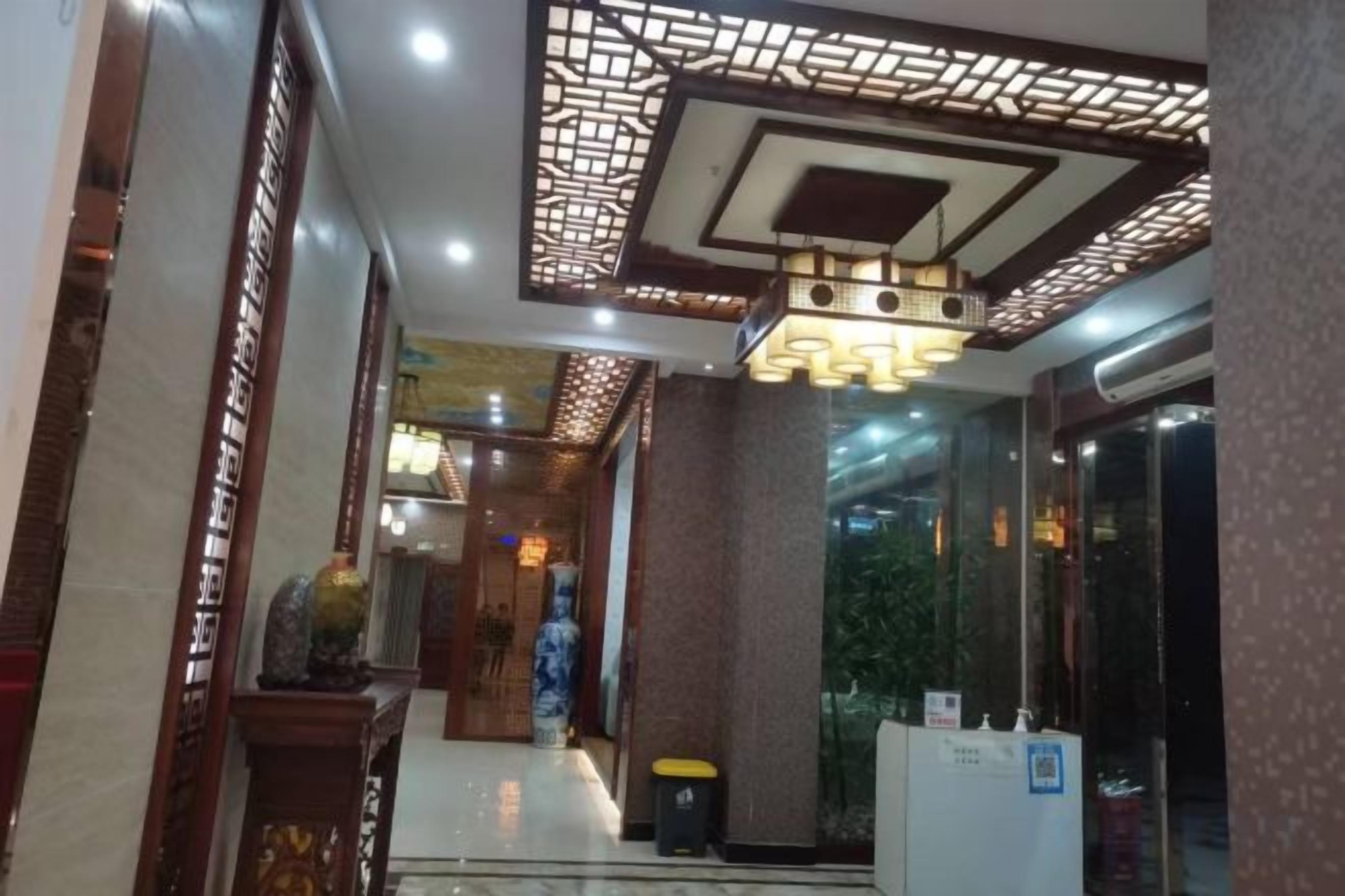 Um hall de hotel com balcão de recepção, teto decorativo e porta de vidro que dá para o exterior.