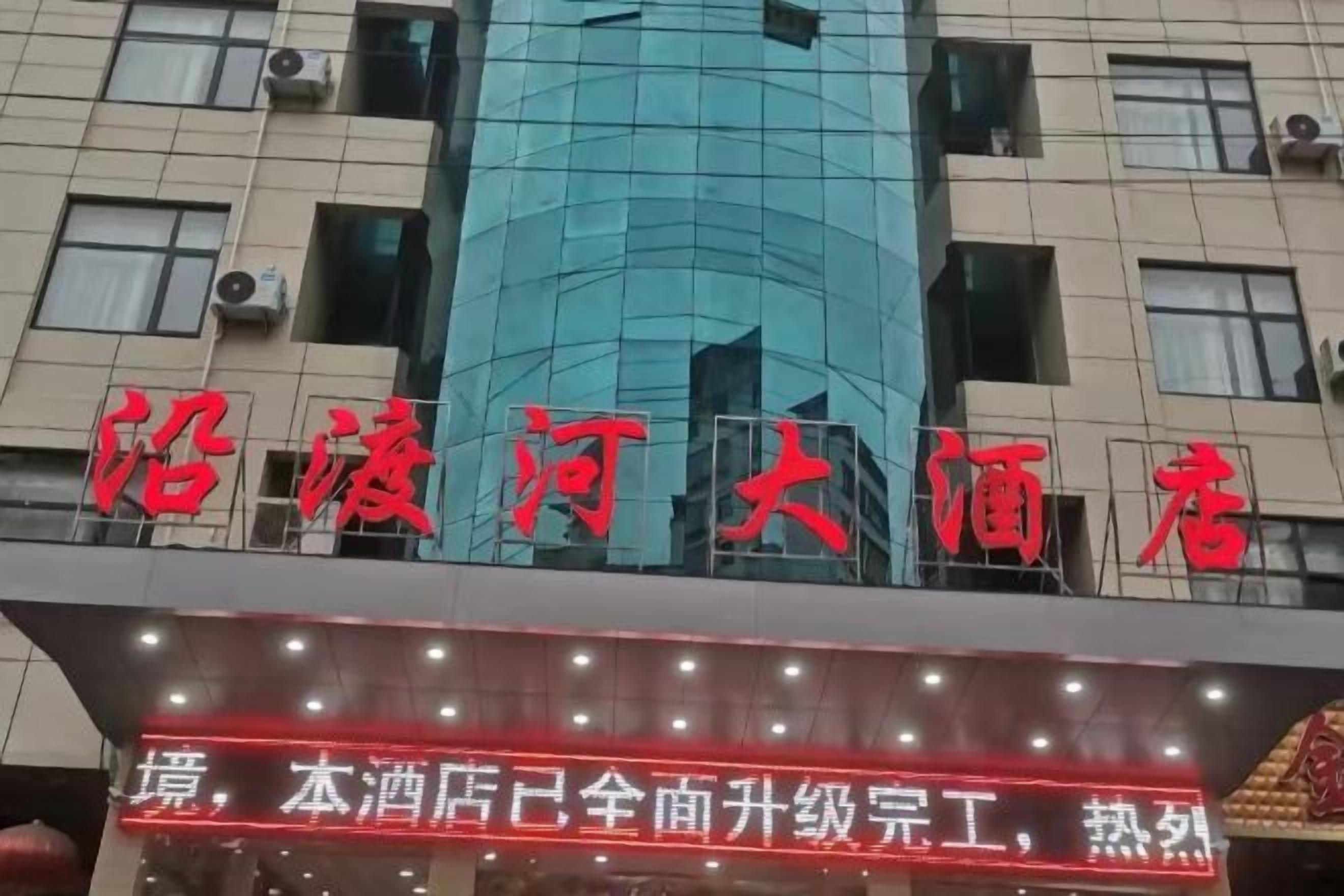 A hotel sign with red lettering on a building facade.