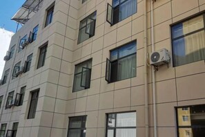 En bygning med flere etager, en beige facade, mange vinduer og ventilationsanlæg på ydersiden.