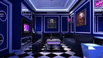 A room with a checkered floor, a flat-screen TV, a sofa, and a coffee table.