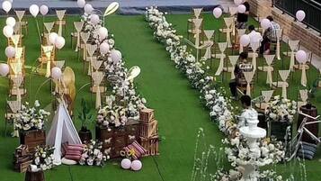 An outdoor event setup with tables, chairs, and floral arrangements.