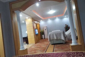 A hotel room with a bed, a desk, a television, and a potted plant. - Yanduhe Hotel (Badong)
