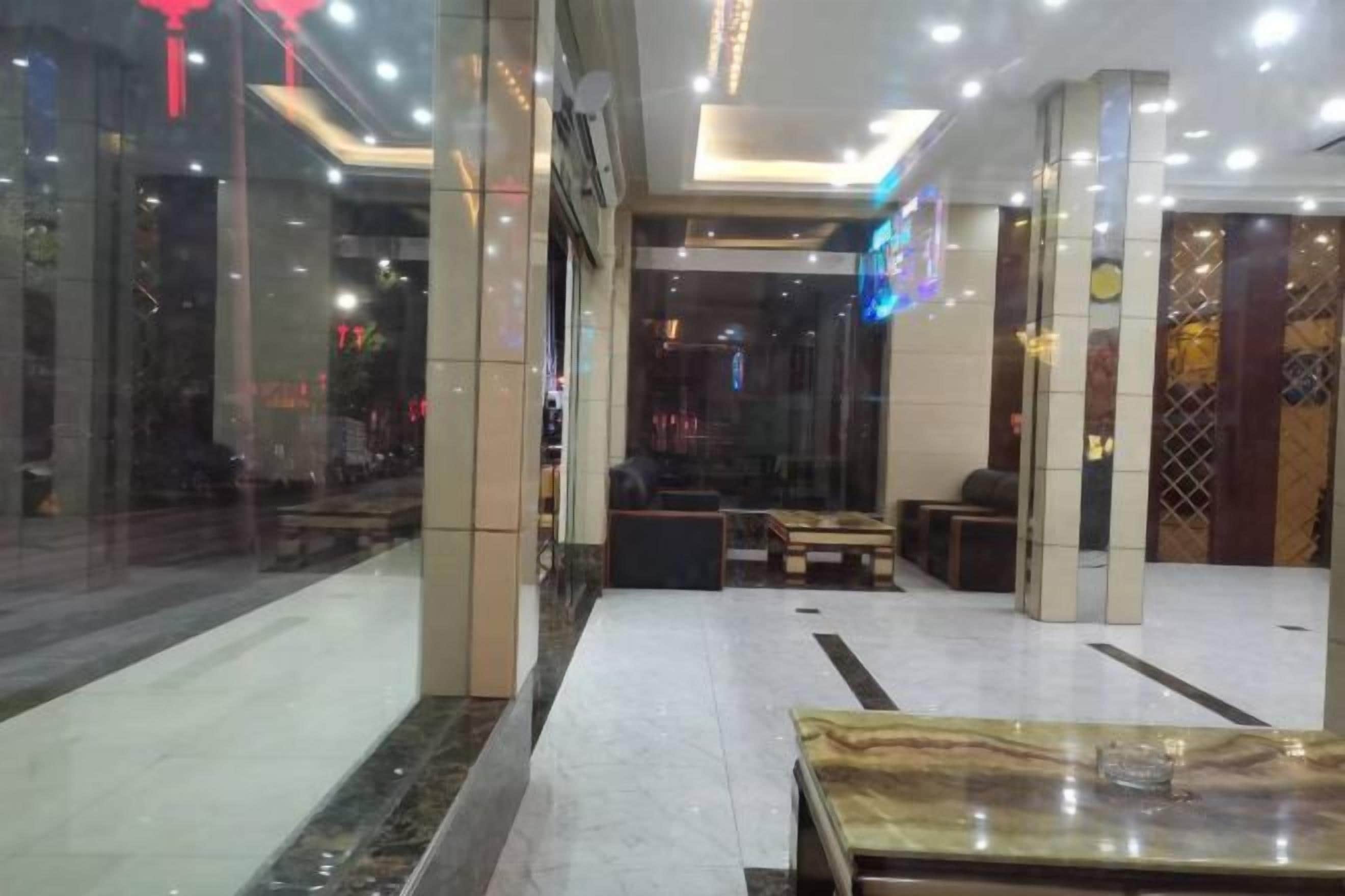 A hotel lobby with a marble floor, seating areas, and a reception desk.