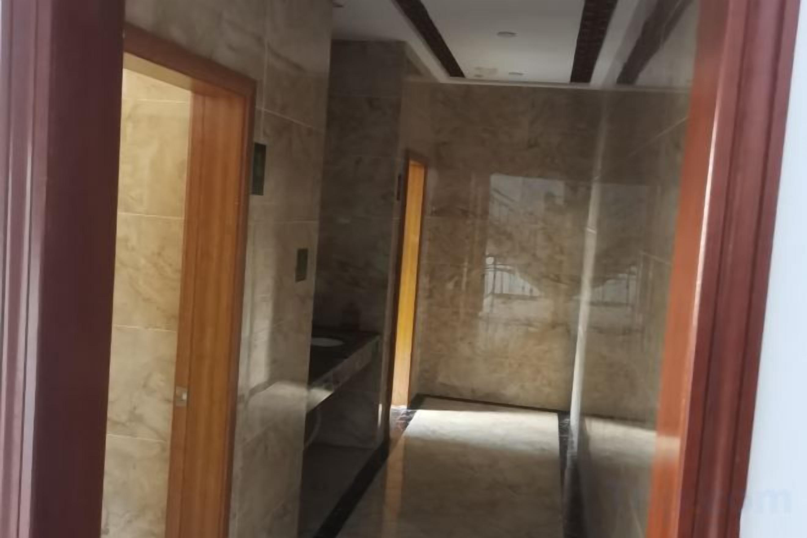A corridor with marble walls and a wooden door on the left.