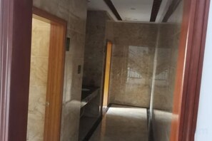 A corridor with marble walls and a wooden door on the left. - Yanduhe Hotel (Badong)