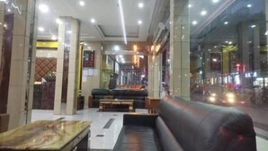 Een moderne lobby met een zithoek, een receptiebalie en uitzicht op de straat.