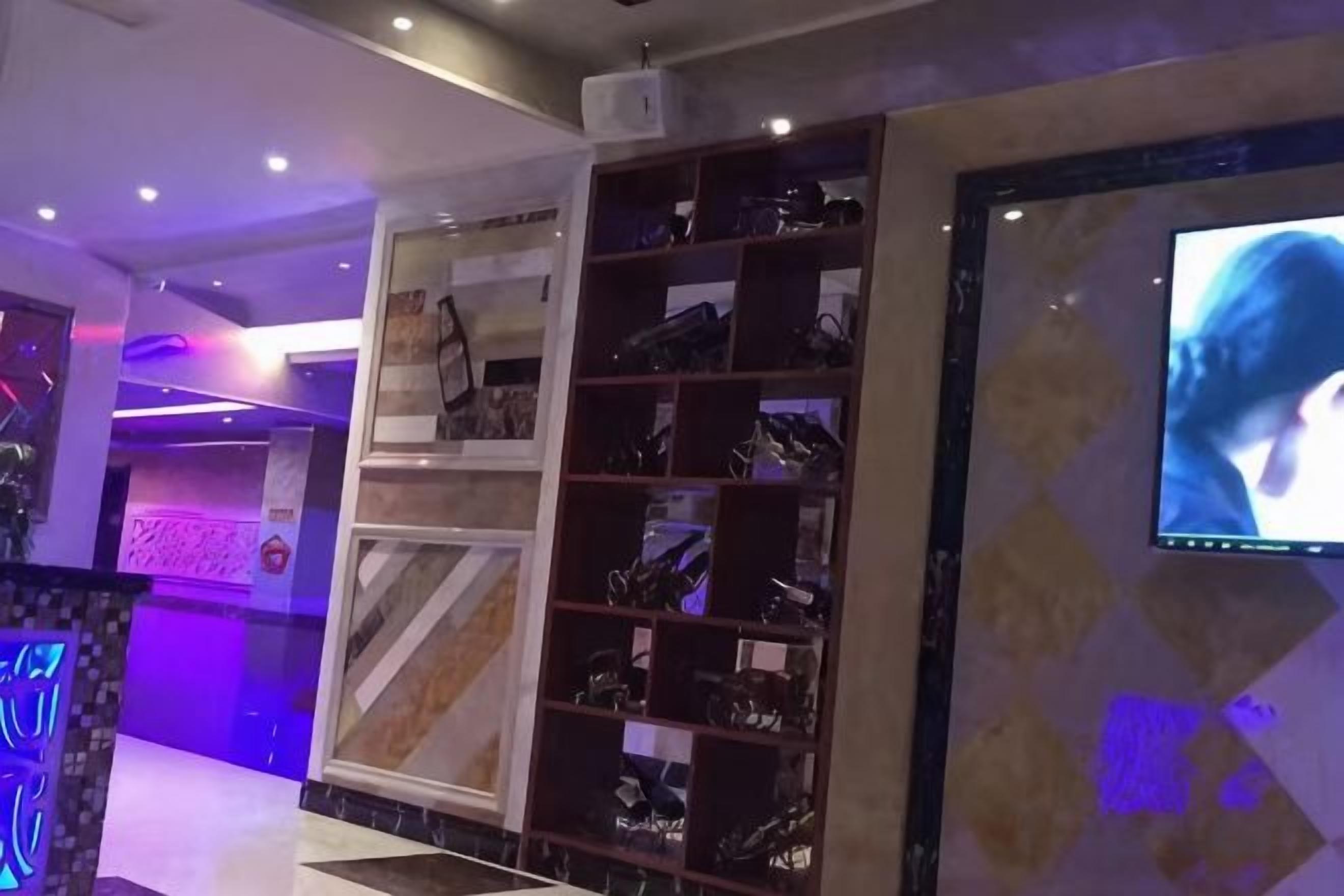 A shoe display area with multiple shelves, a television screen, and a patterned wall.