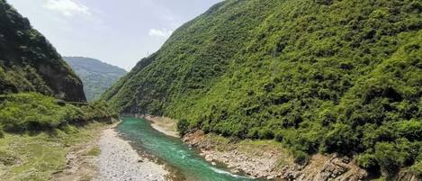 A river flowing through a valley with steep, forested hills on either side.