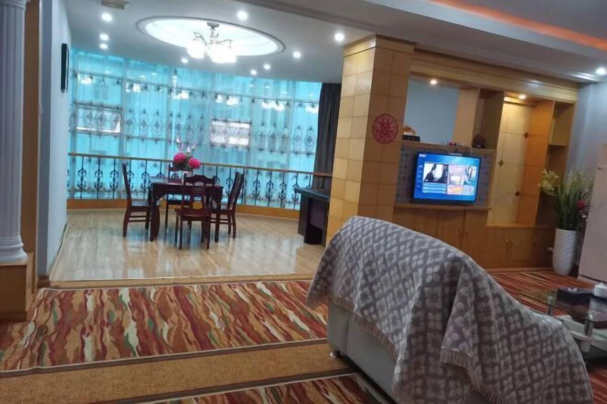 Un vestíbulo de hotel con zona de comedor, televisor y alfombra estampada.