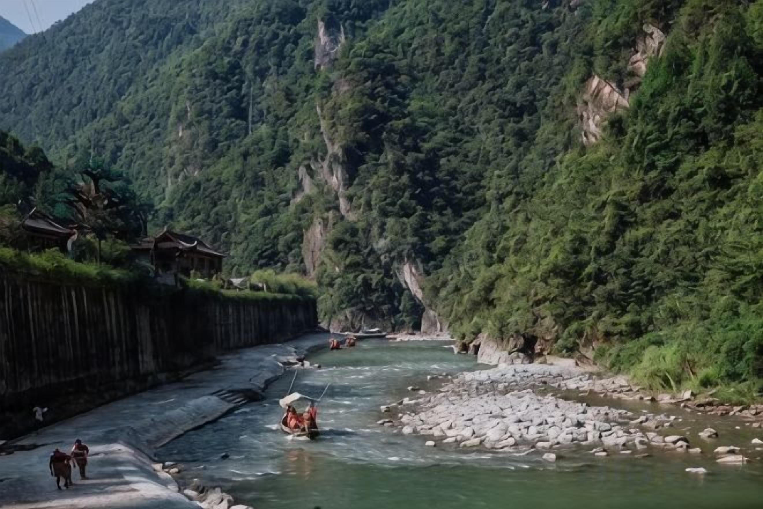 Un fiume con barche, una passerella di legno e montagne sullo sfondo.