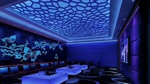 Een moderne lounge met een geometrisch plafondontwerp, zithoeken en een patroon vloer.