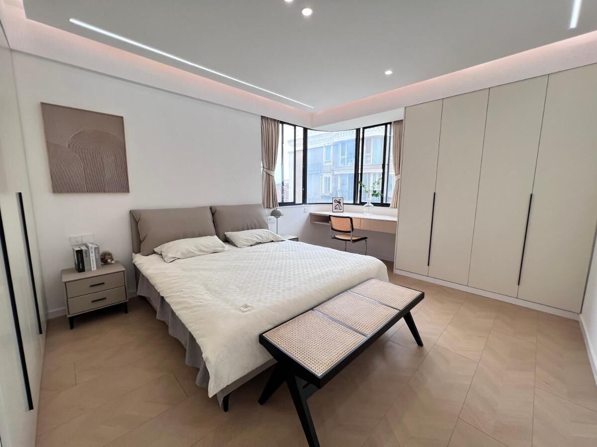 Ein modernes Schlafzimmer mit einem großen Bett, einem Schreibtisch und einem Kleiderschrank.