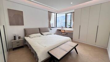 Ein modernes Schlafzimmer mit einem großen Bett, einem Schreibtisch und einem Kleiderschrank.