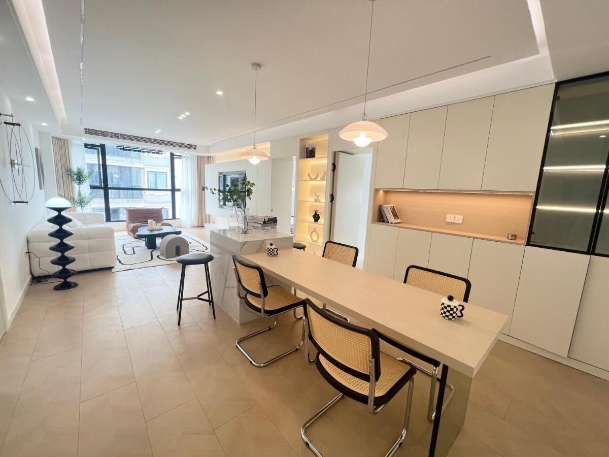 A modern kitchen with a central island, white cabinetry, and a stainless steel refrigerator.