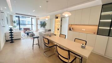 A modern kitchen with a central island, white cabinetry, and a stainless steel refrigerator.