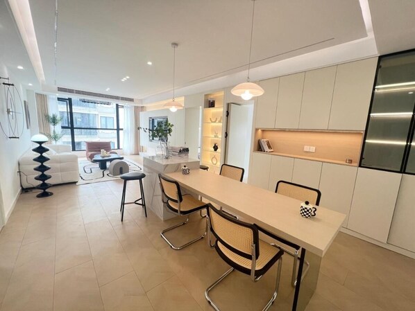 A modern kitchen with a central island, white cabinetry, and a stainless steel refrigerator.