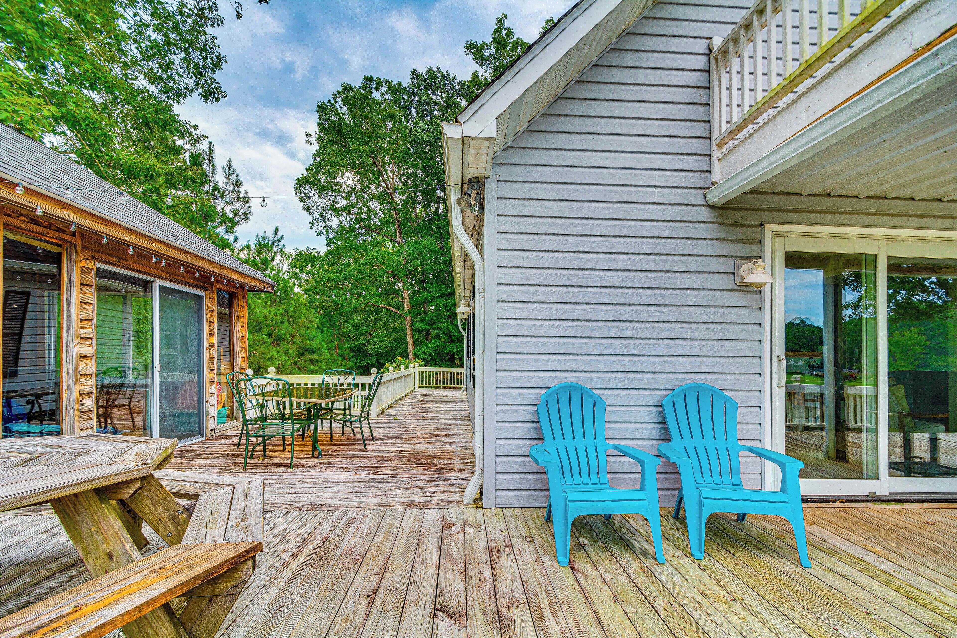 A wooden deck with a table and chairs, a covered patio area, and a building with a sliding glass door.